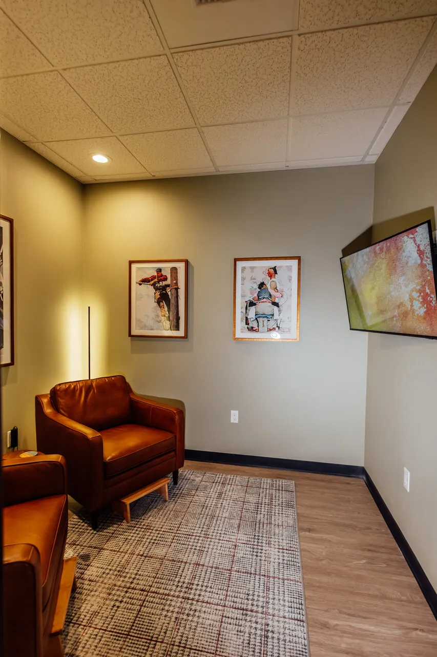 Consultation lounge at Asymmetric Health with leather seating and a wall-mounted display for lab review