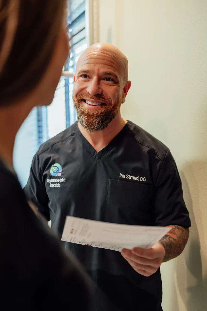 Dr. Ian Strand handing an Asymmetric Health patient her printed Patient Handbook with treatment protocol