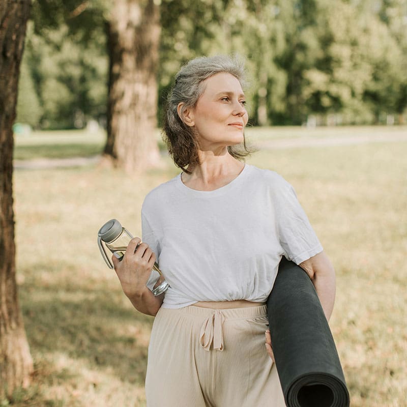 woman-yoga Older woman holding a water bottle and a yoga mat