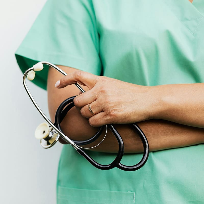 A doctor i n green scrubs holding a stethoscope